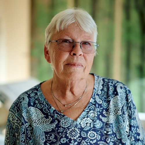 Ein Frau spricht, im Hintergrund eine Waldtapete und ein Pflegebett