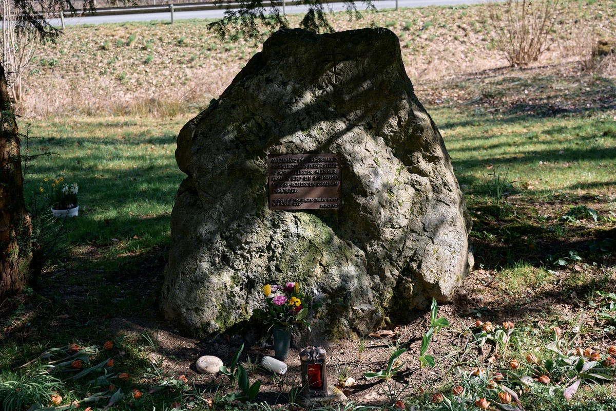 Ein Gedenkstein, davor ein Blumenstrauß und ein Grablicht Ein Gedenkstein, davor ein Blumenstrauß und ein Grablicht